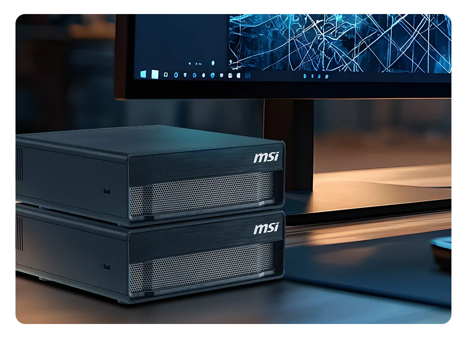 Compact edge AI workstations stacked beside a monitor in an office